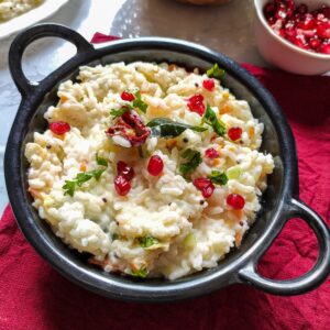 curd rice garnished with pomegranate seeds served in a black wok kept on a red table napkin