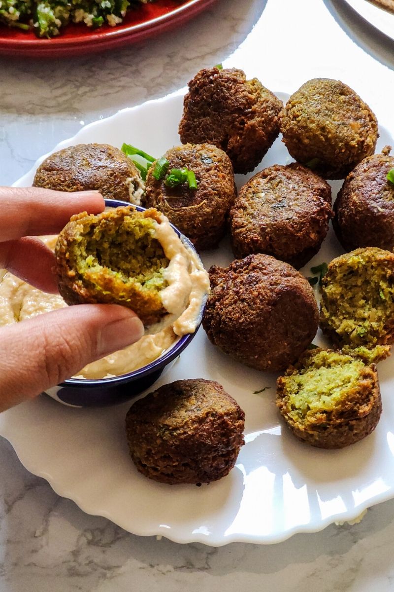 Half a piece of falafel picked over a plate of falafel