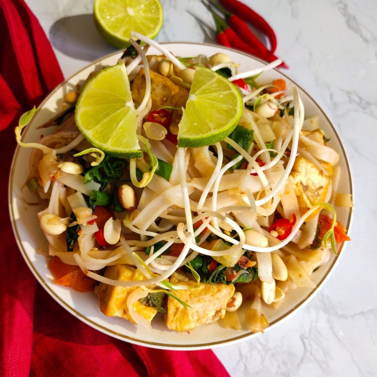 Vegan Pad Thai served in a white bowl garnished with lime wedges