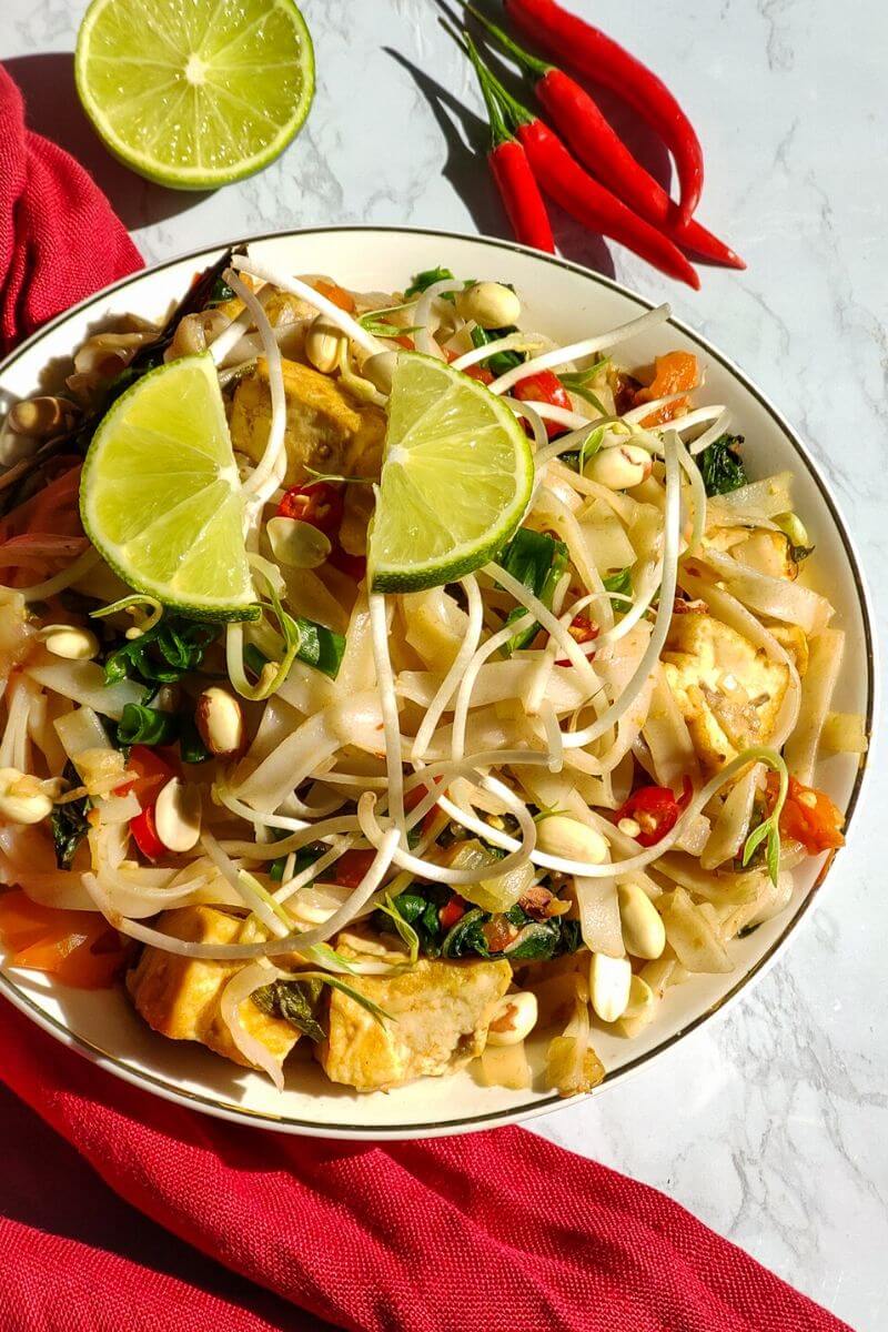 Vegan Pad Thai served in a white bowl garnished with lime wedges