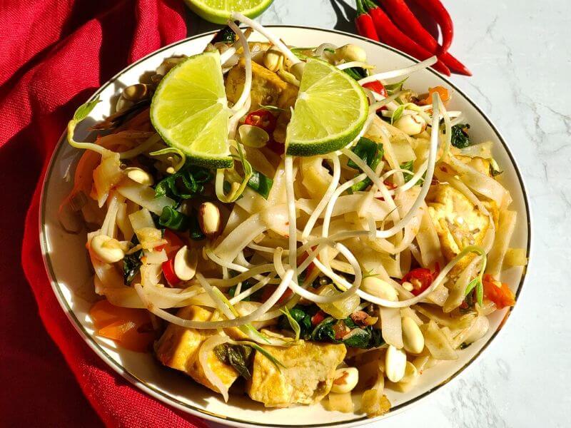 Vegan Pad Thai served in a white bowl garnished with lime wedges