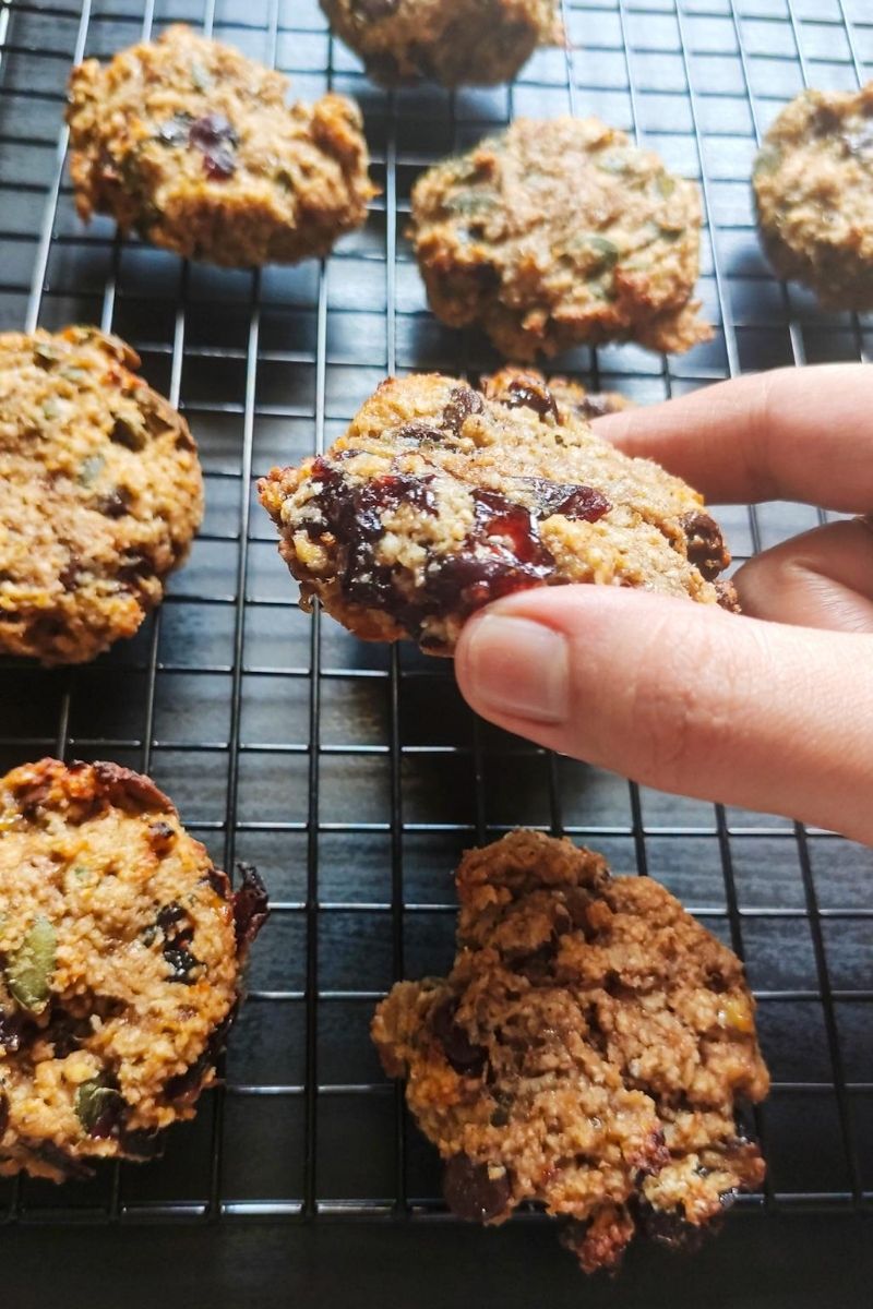 One breakfast cookie lifted above a rack of cookies