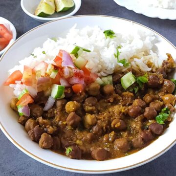 kala chana masala served in a bowl with rice and salad.
