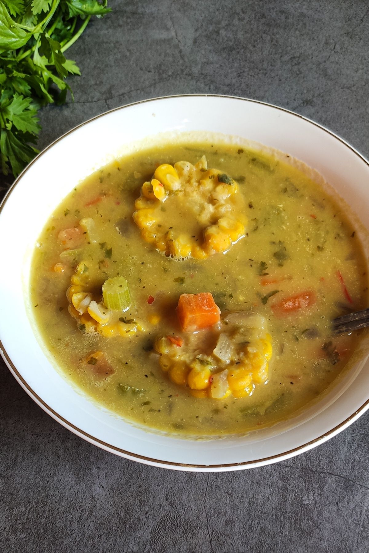 Trinidad corn soup in a bowl with cilantro in the background