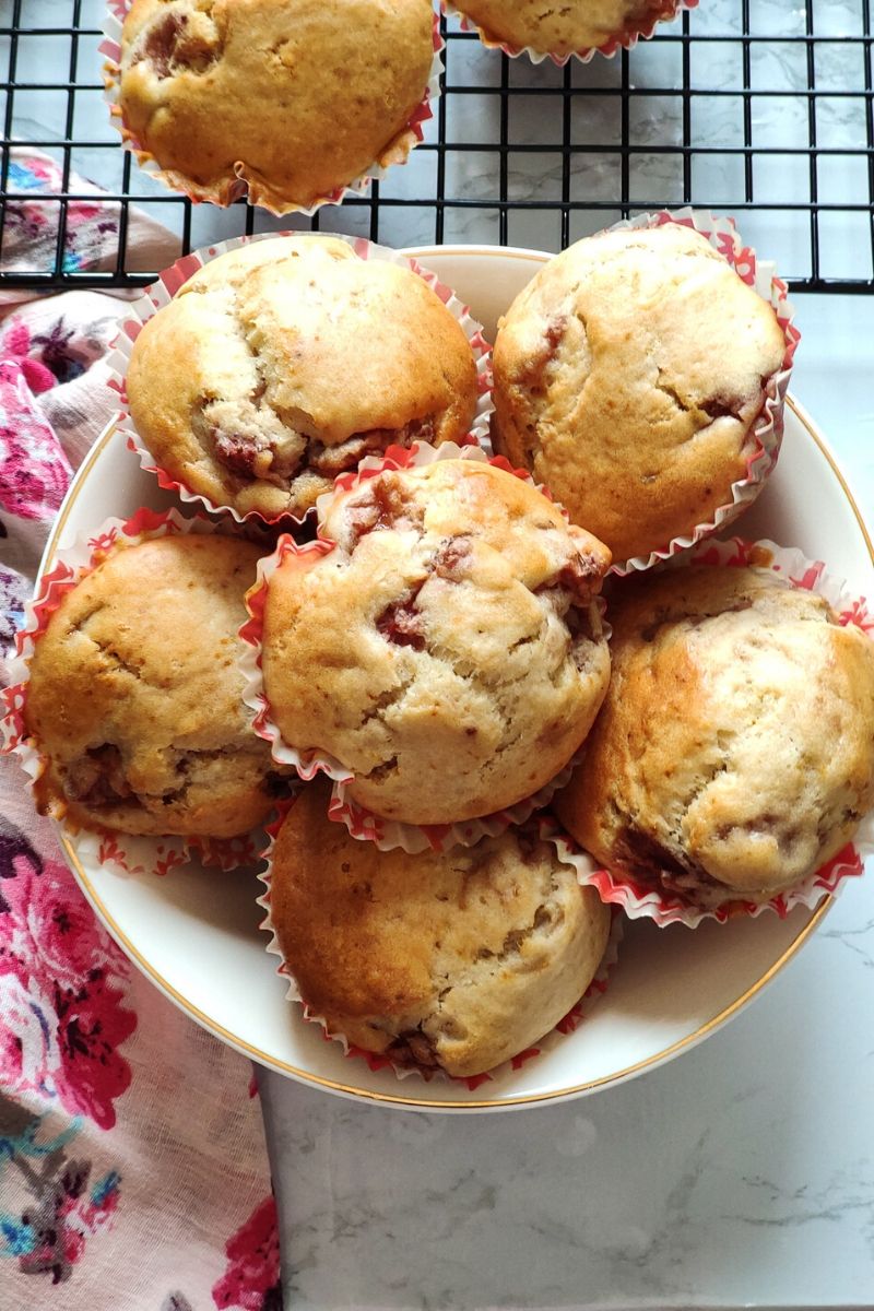 Vegan strawberry muffins kept in a white bowl on top of a pink floral table napkin