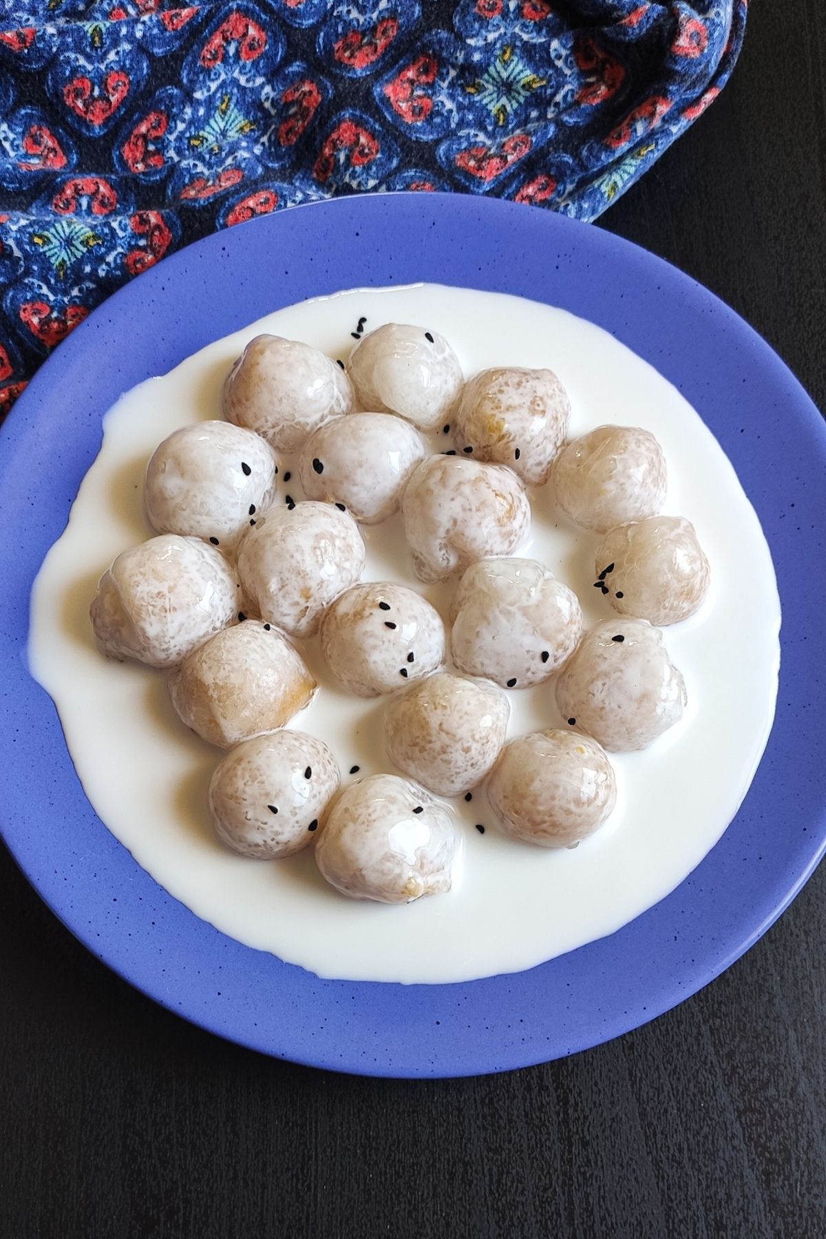 sweet potato dumpling garnished with black sesame seeds served on a blue plate