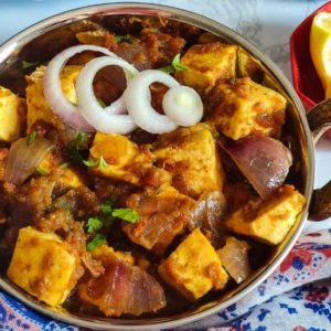 Paneer do pyaza garnished with onion rings served in a bowl