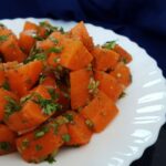 Moroccan carrot salad garnished with chopped cilantro served on a white plate