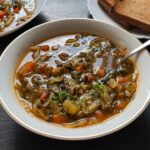 Healing cabbage soup served in a white bowl with bread