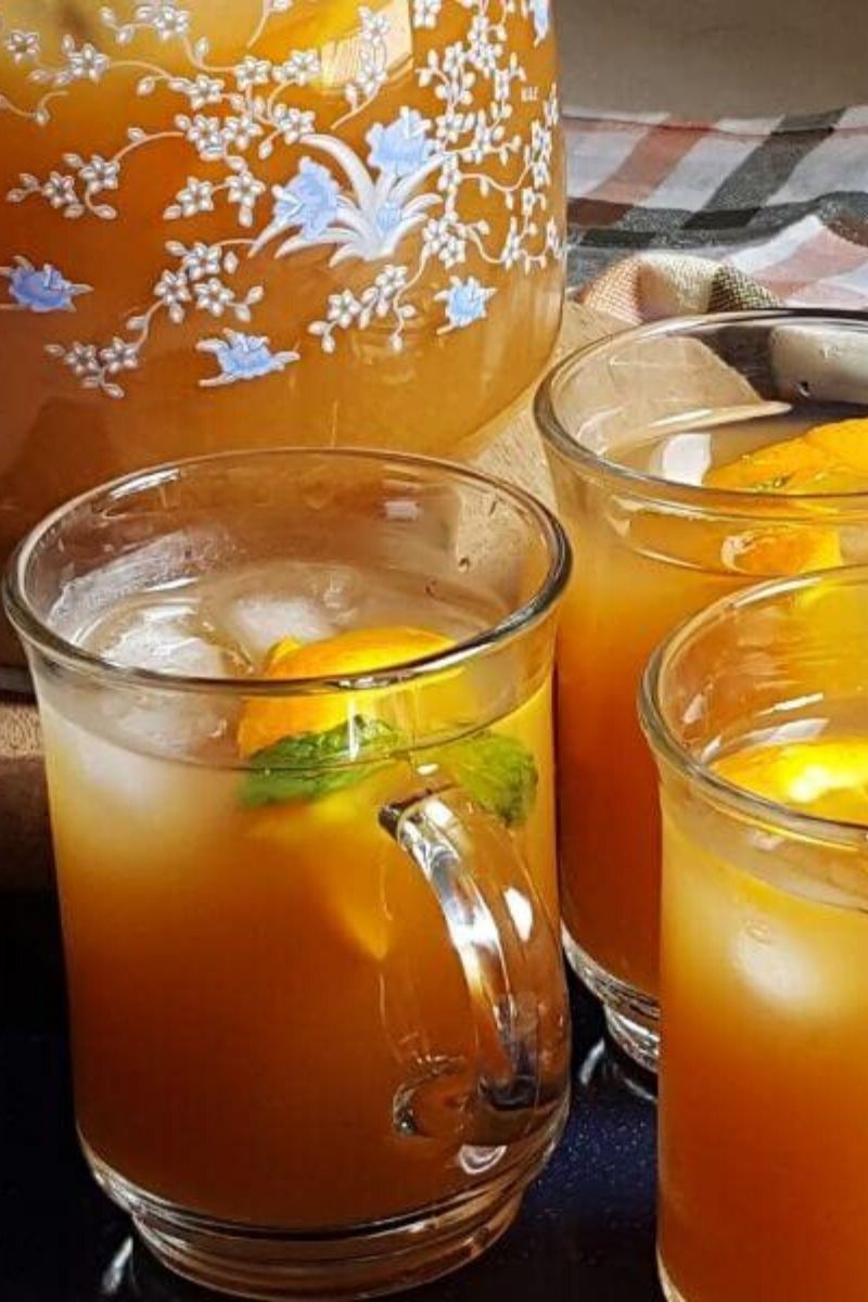 orange iced tea served in three glasses and a pitcher