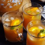 orange iced tea served in three glasses and a pitcher