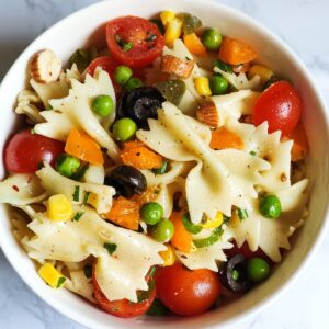 Easy vegan pasta salad made with farfalle, cherry tomatoes, and vegetables.