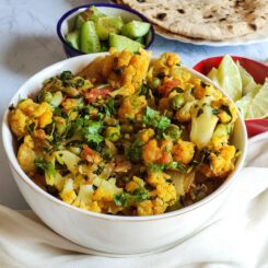 Gobhi matar methi served in a white bowl with salad and chapati in the background