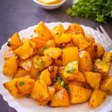 Moroccan spiced potatoes served on a white plate with a fork.