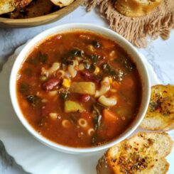 Vegan Minestrone Soup served in a white bowl with toasted garlic bread