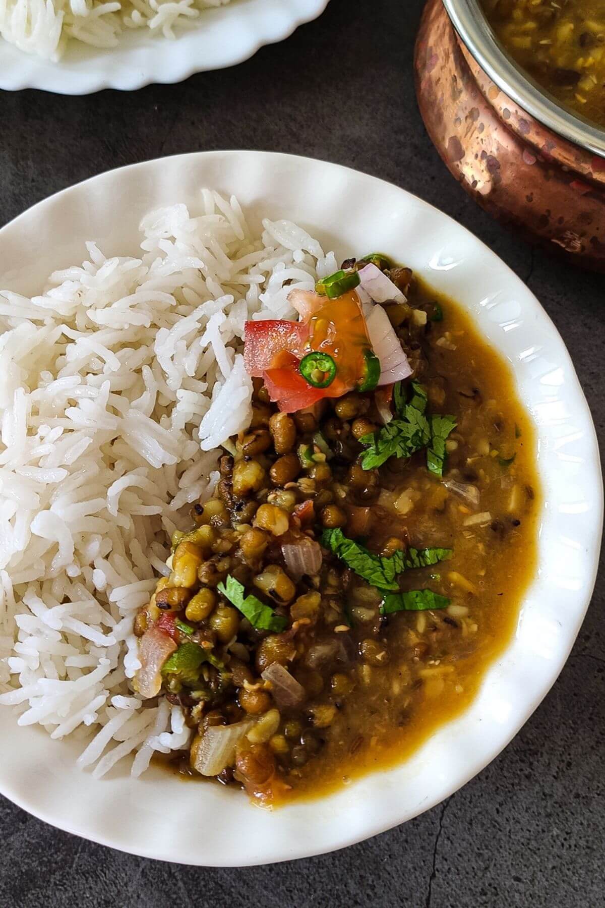 Indian mung bean curry served with rice and salad in a white bowl.