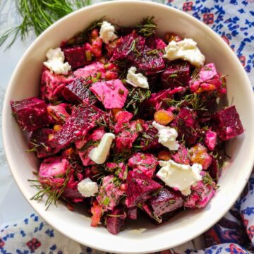 Mediterranean beetroot and feta cheese salad garnished with dill served in a white bowl.