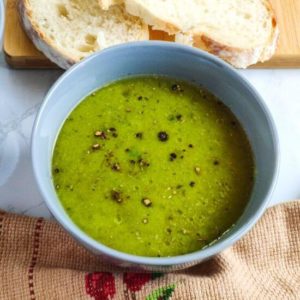 Green peas soup served in a grey bowl with bread slices