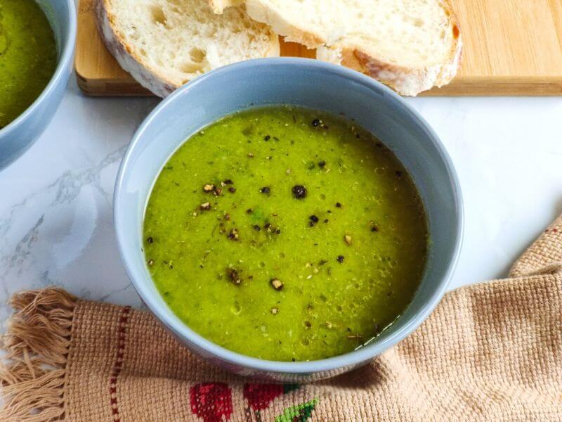 Green peas soup served in a grey bowl with bread slices