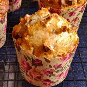 Vegan banana muffin in a floral paper muffin mold kept on a cooling rack and more muffins in the background