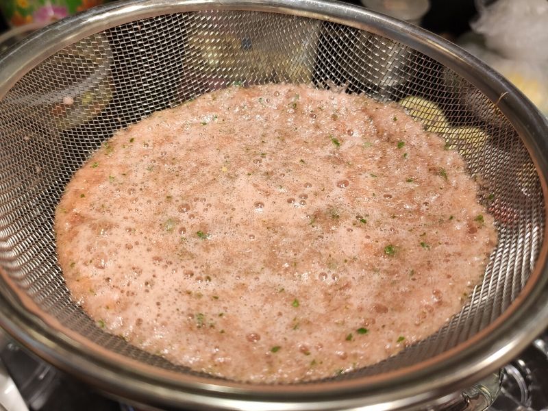 watermelon lemonade getting strained with a large strainer