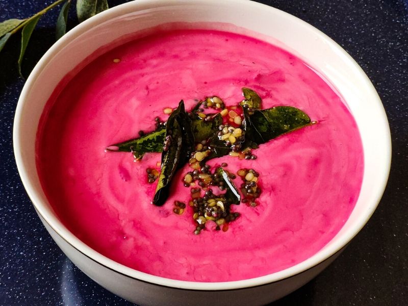 Raita made with beetroot, tempered with curry leaves and mustard seeds served in a white bowl