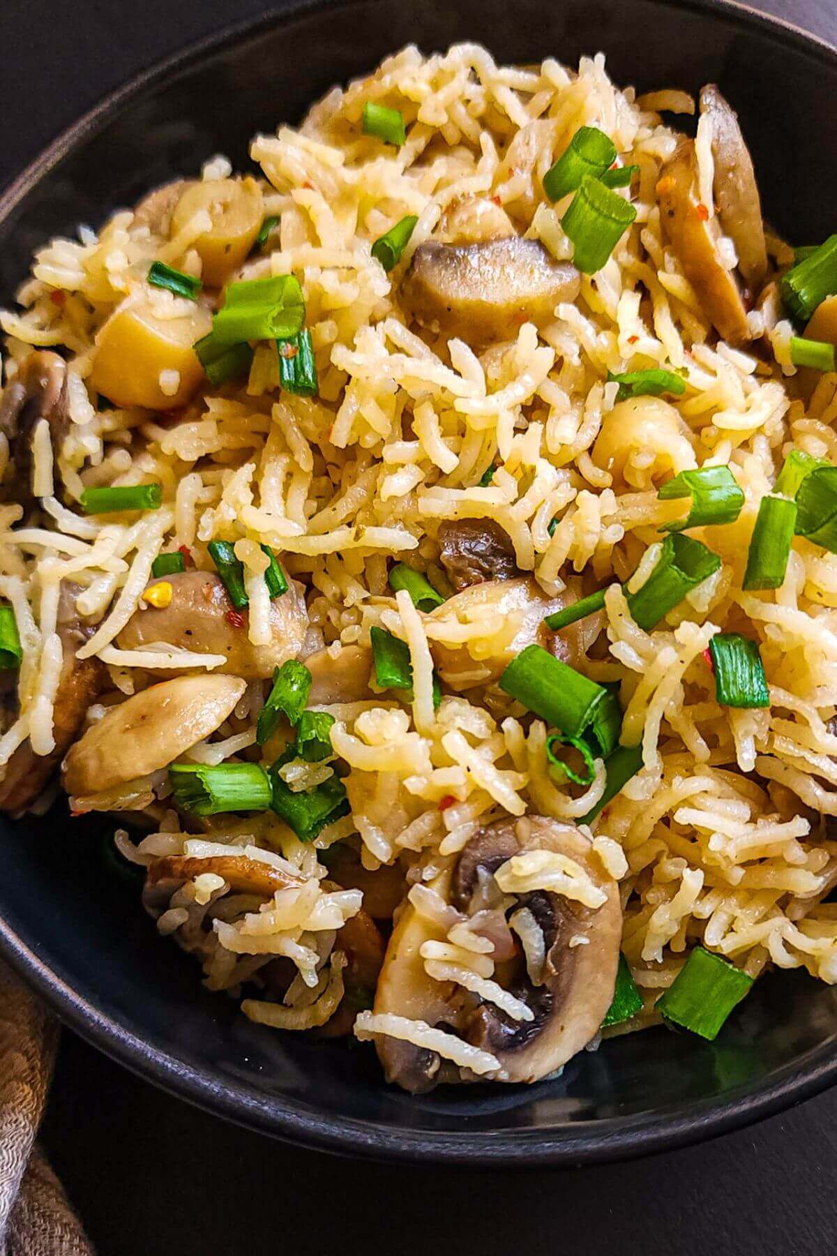 Close up shot of mushroom rice garnished with chopped spring onion greens.