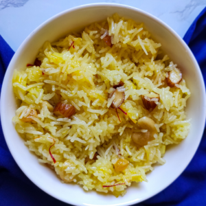 Indian style sweet rice garnished with dry fruits served in a white bowl kept on a blue table napkin