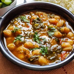 Chickpea spinach curry garnished with coriander leaves served in a black bowl