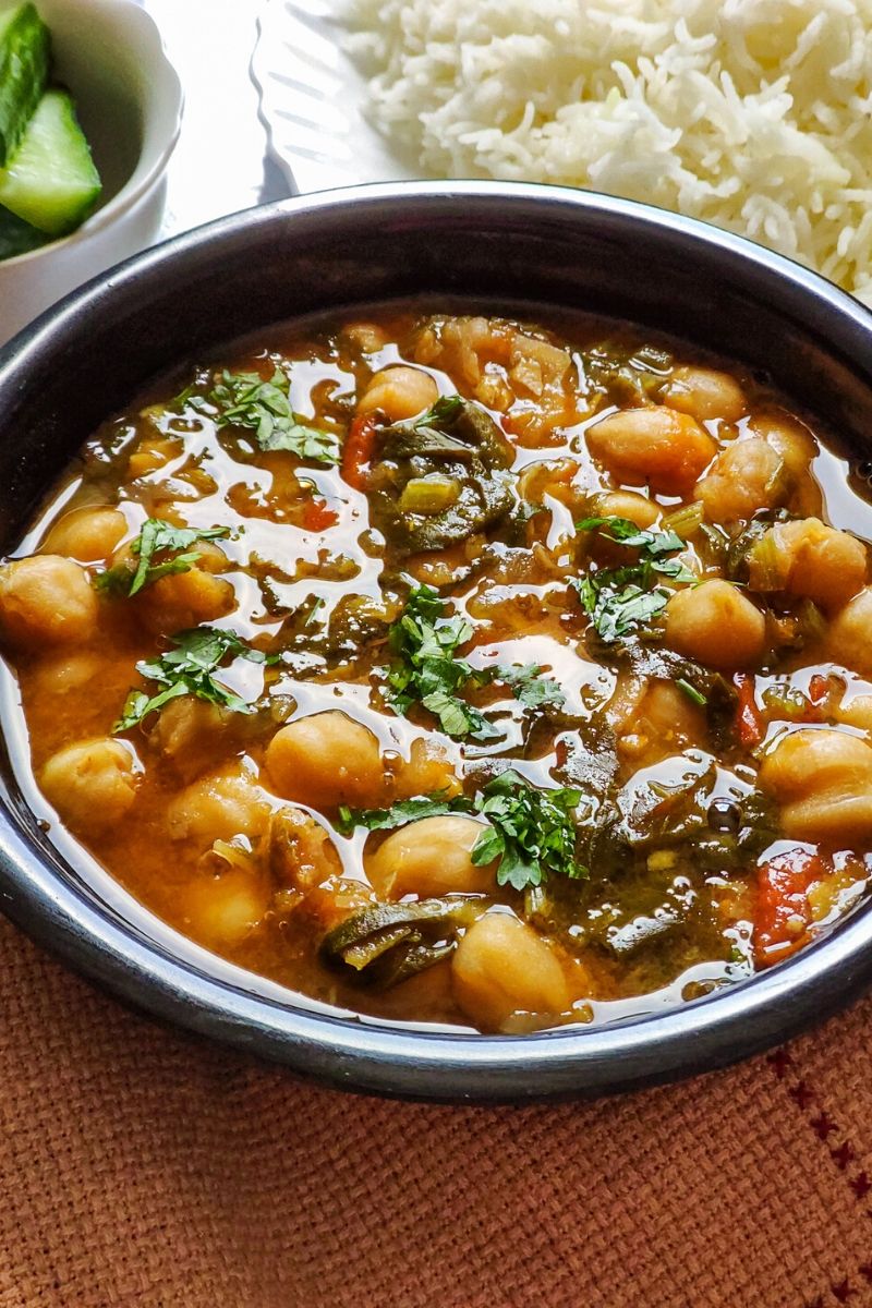 Chickpea spinach curry garnished with coriander leaves served in a black bowl