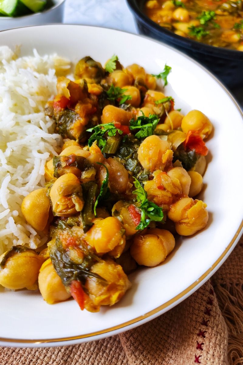 Chickpea spinach curry served with rice in a shallow white bowl