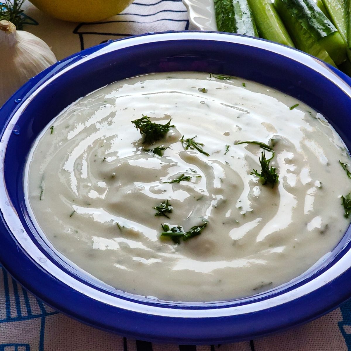 Greek Yogurt dip garnished with chopped dill served in a blue bowl