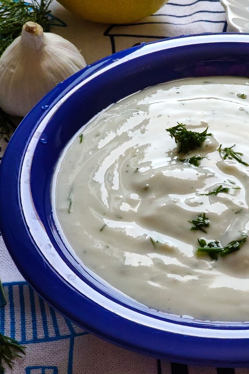 Greek Yogurt dip garnished with chopped dill served in a blue bowl