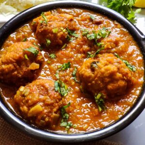 lauki ke kofte garnished with chopped coriander leaves served in a black bowl