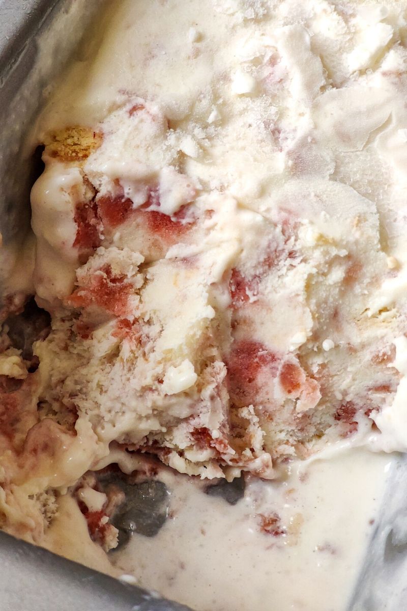 Strawberry cheesecake ice cream in a baking tin with some portion scooped out
