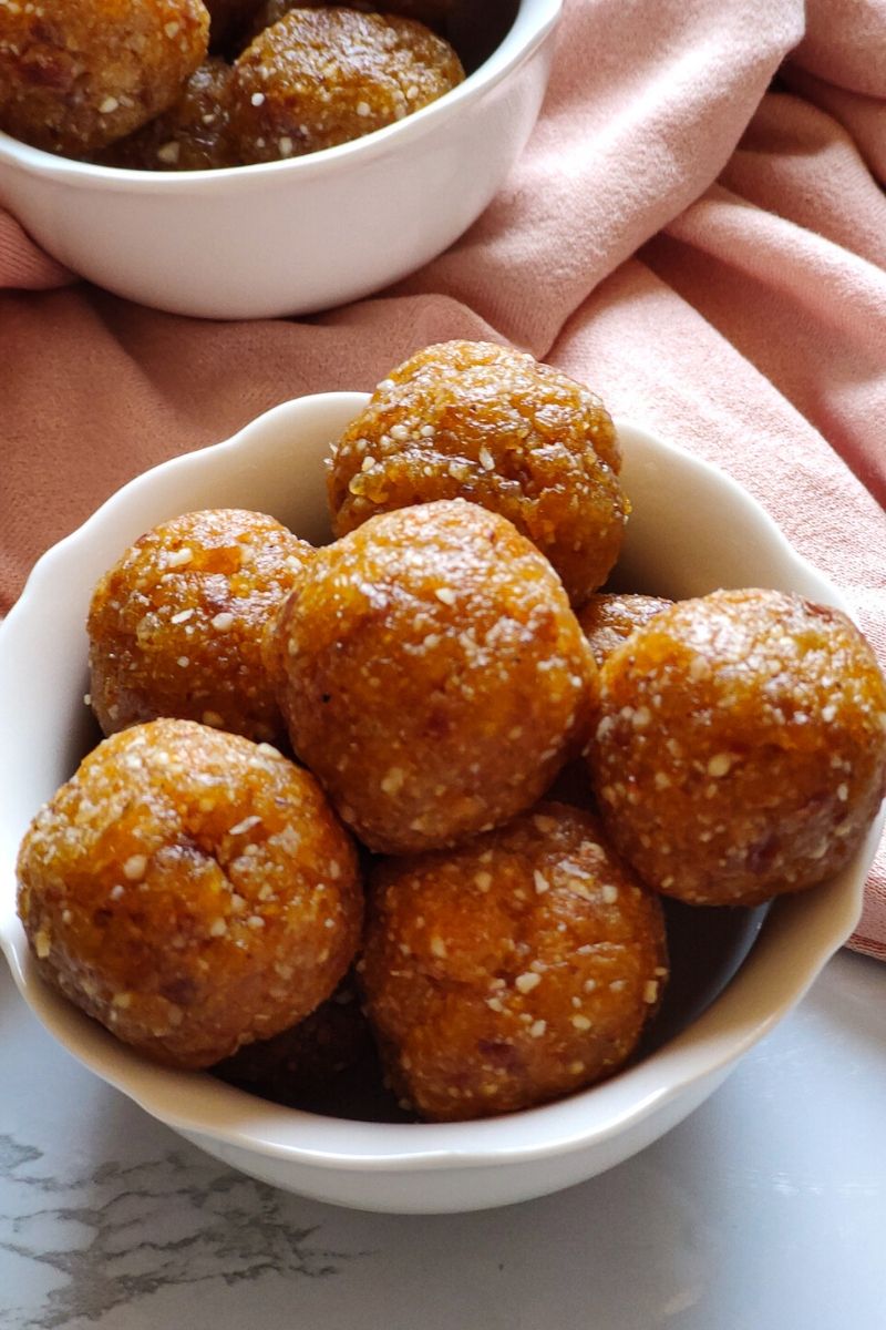 Apricot energy balls served in a white bowl and a portion of another bowl visible in the background
