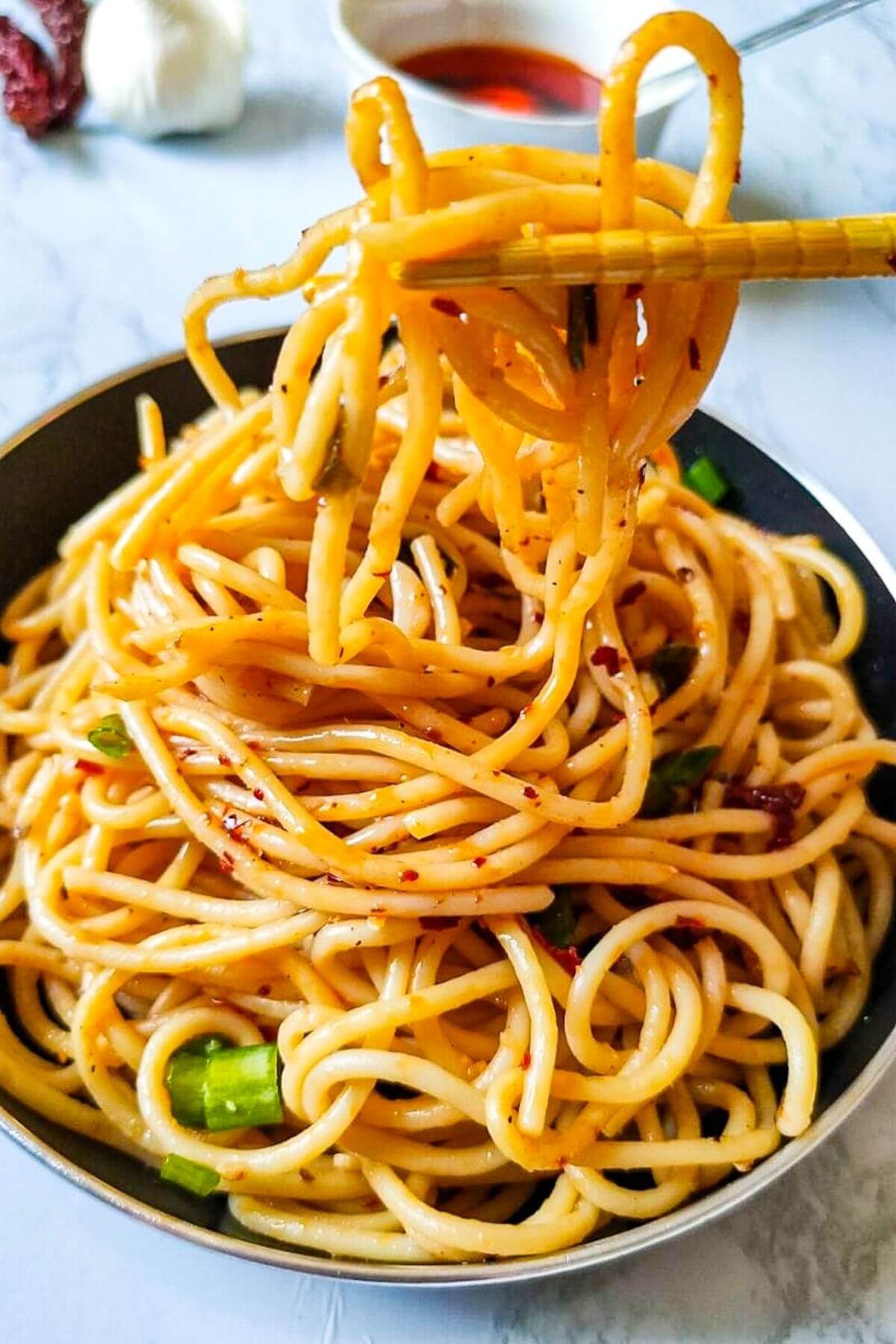 chili garlic noodles picked up with chopsticks