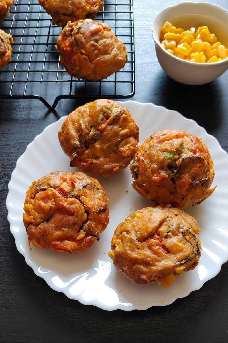 four savoury muffins kept on a whote plate with a cooling rack in the background