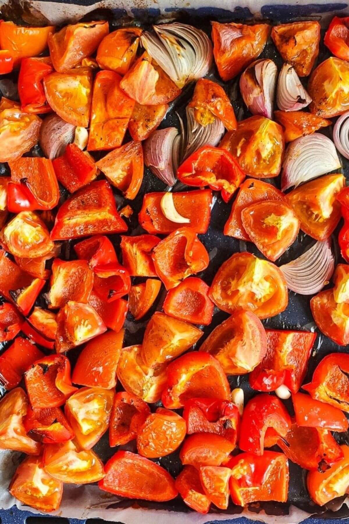 Roasted tomato, red bell pepper, onion, and garlic on a baking tray