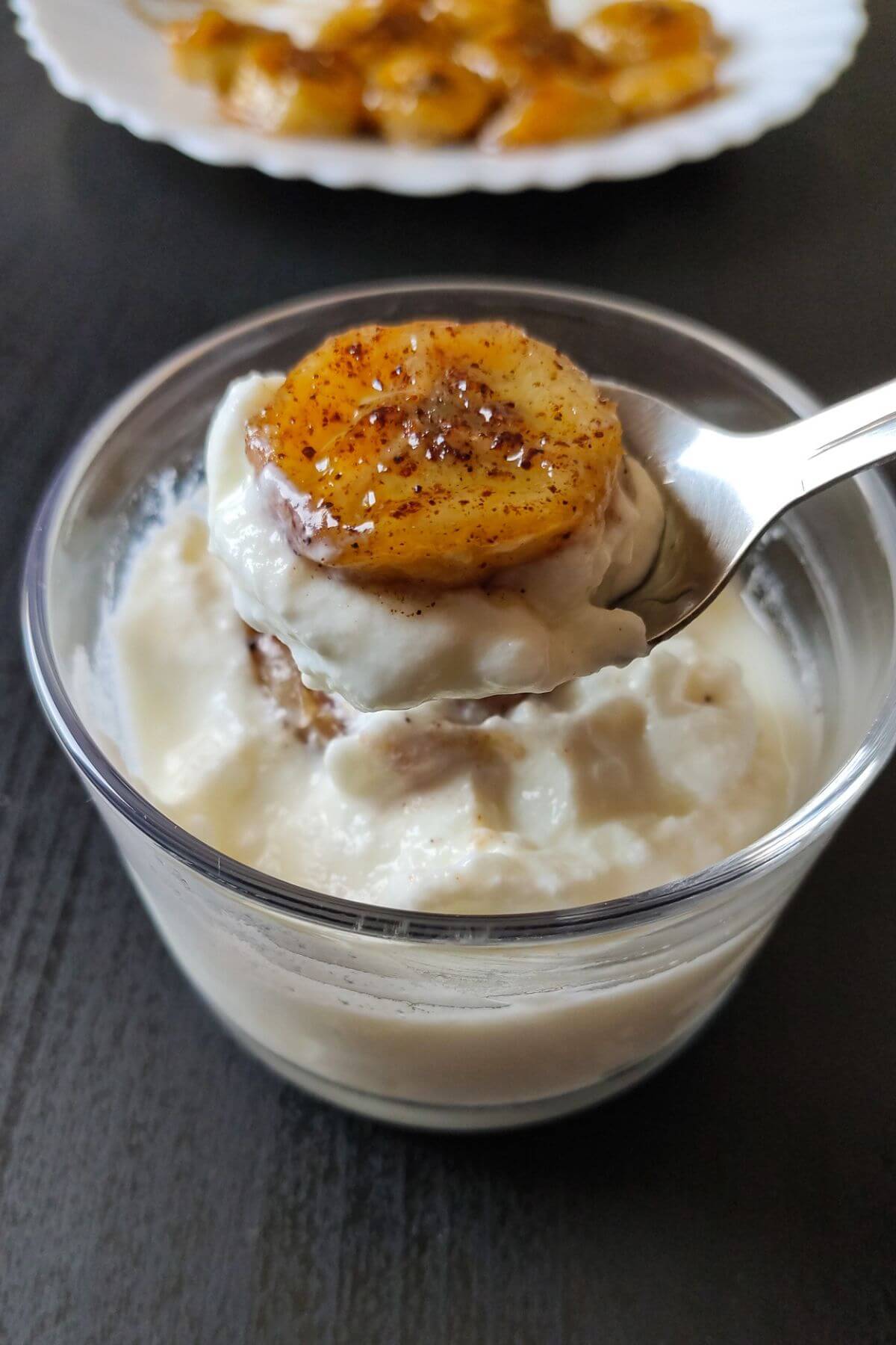 A slice of caramelized banana on top of a spoon full of yogurt