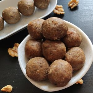 vegan energy balls served in a white bowl and some more kept on a plate in the background