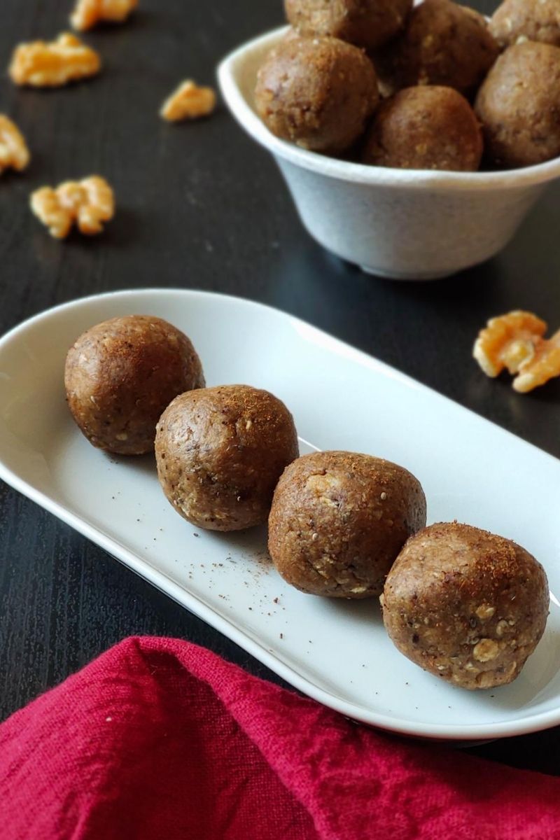 vegan energy balls served on a white snack plate and more kept in a bowl in the background