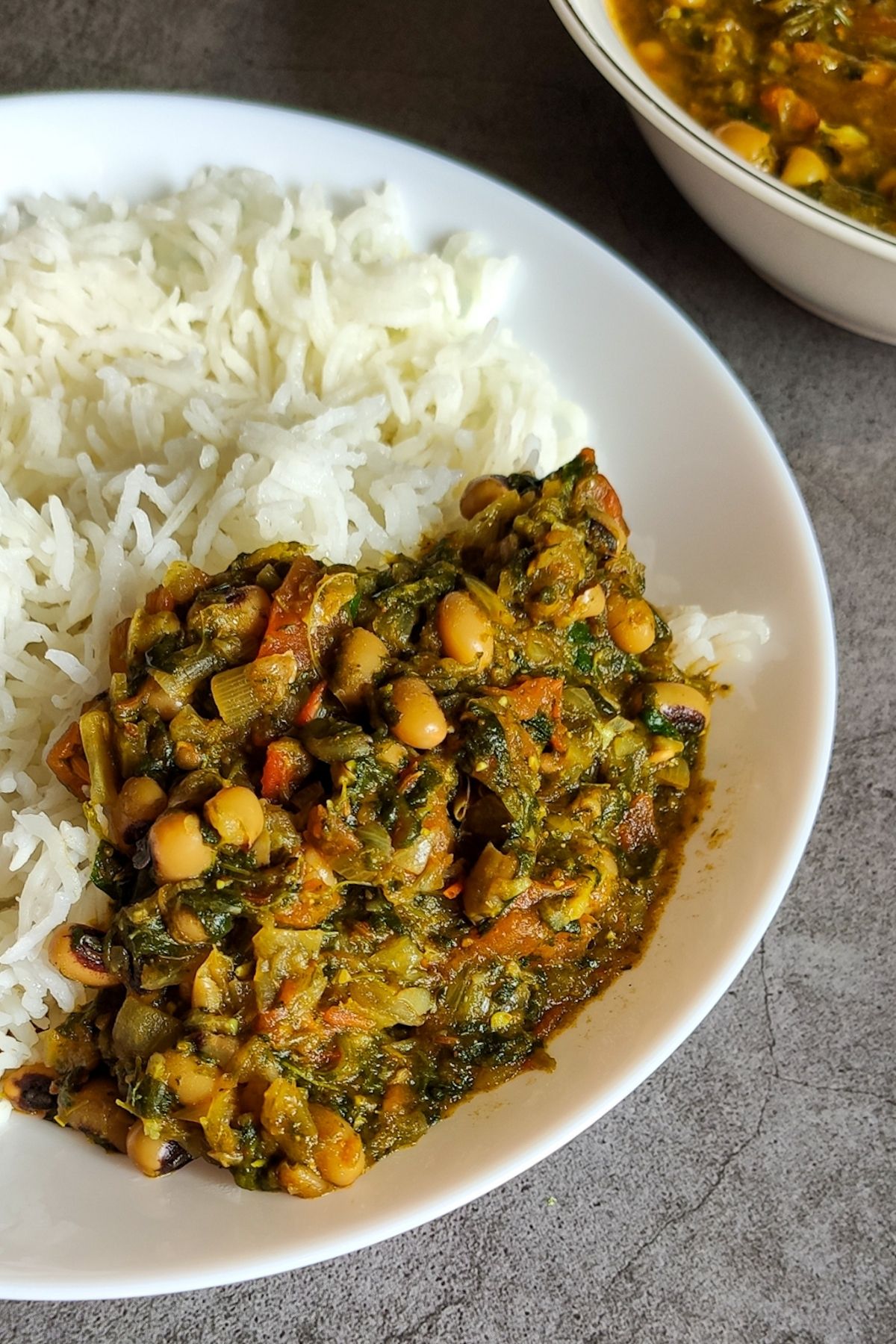black eyed peas and spinach curry served with rice on a white plate