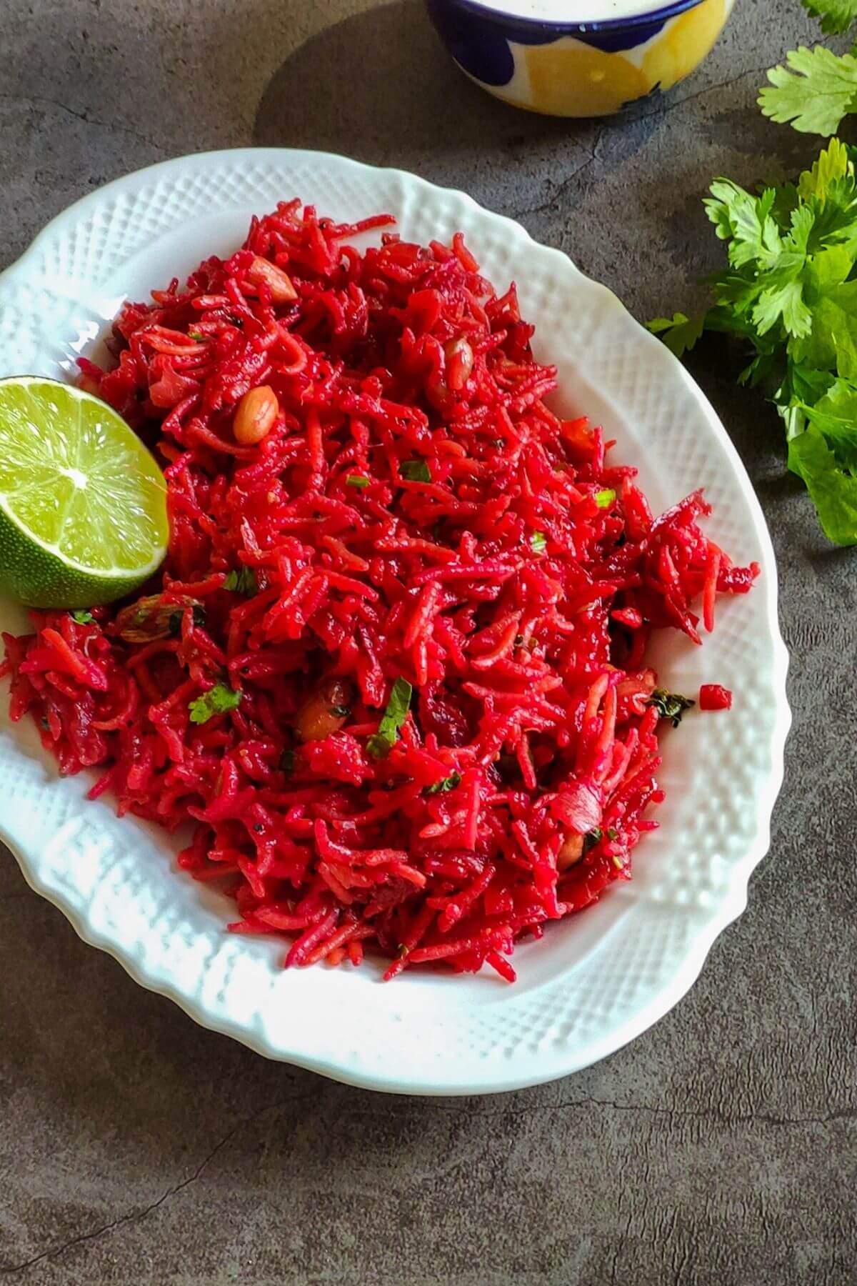 Beetroot rice garnished with a lime slice served on a white plate