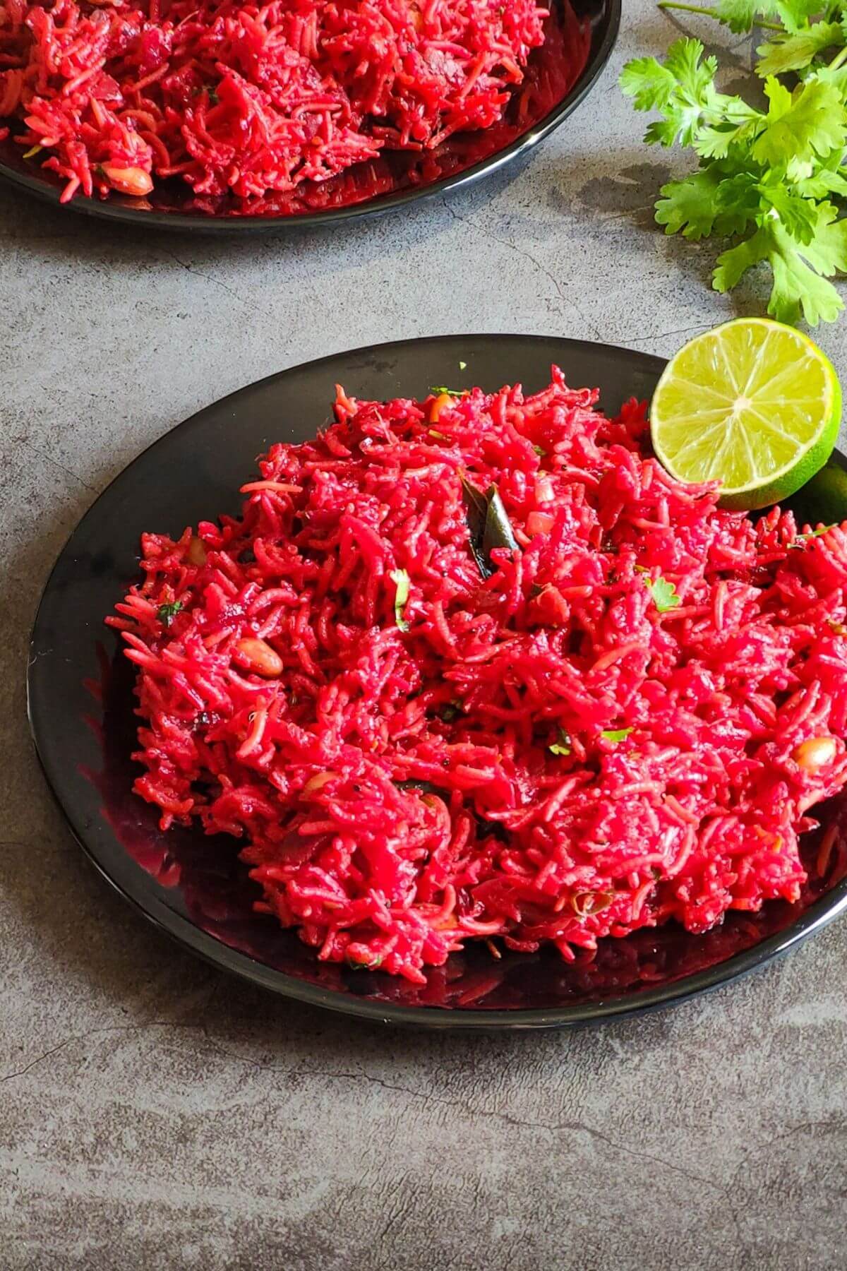 Beetroot rice garnished with a lime slice served on a black plate