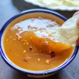 mango chili sauce getting scooped out from a bowl with a potato chip