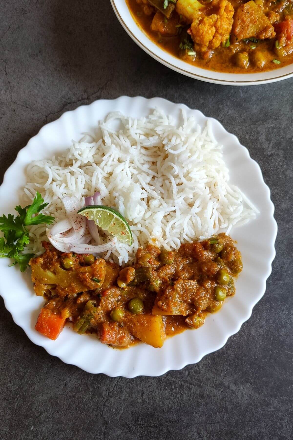Mixed vegetable curry served with rice on a white plate