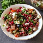Mediterranean lentil salad served in a bowl with fresh herbs in the background