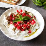 Garlic labneh dip garnished with pomegranate, za'atar, and mint leaves