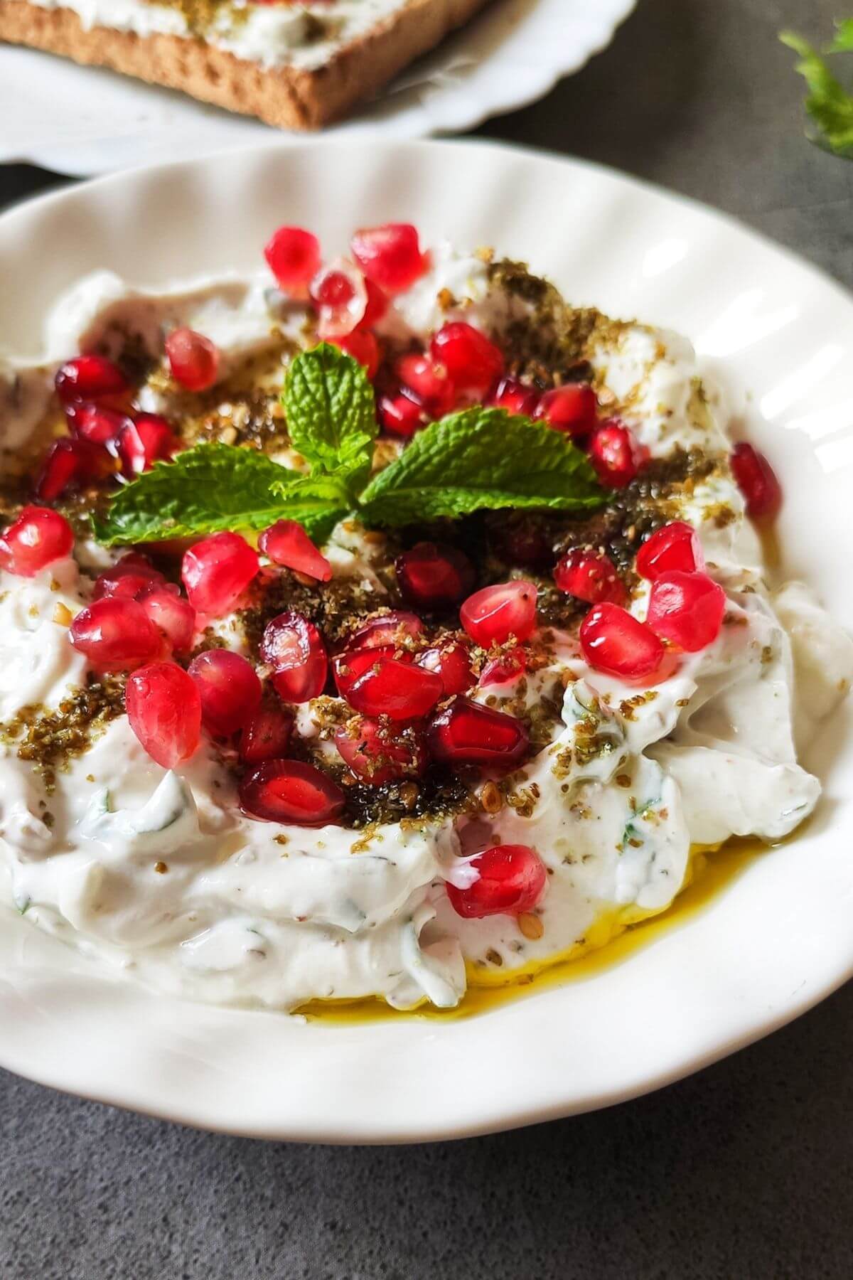 Garlic labneh garnish with za'atar, olive oil, pomegranate, and mint leaves